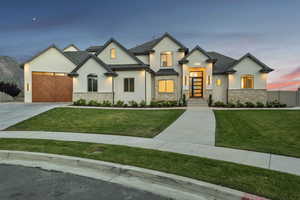 View of front of property featuring stucco siding, a shingled roof, a lawn, an attached garage, and driveway