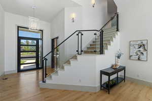 Foyer entrance with a towering ceiling, visible vents, stairway, and wood finished floors