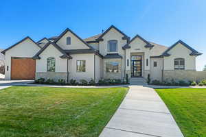 French country style house with stucco siding, stone siding, and a front yard