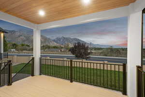 Wooden deck with covered porch, a lawn, and a mountain view