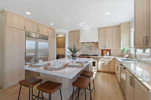 Kitchen featuring light brown cabinets, a sink, custom exhaust hood, and high quality appliances