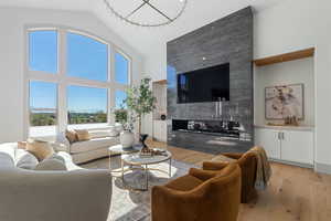 Living room featuring light wood finished floors, high vaulted ceiling, and a high end fireplace