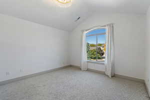 Unfurnished room featuring light carpet, baseboards, visible vents, lofted ceiling, and an inviting chandelier