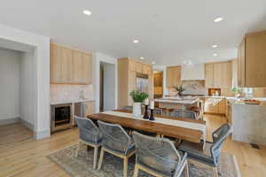 Dining room featuring light wood-style floors, wine cooler, and recessed lighting