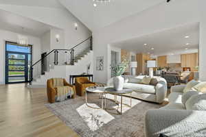 Living area featuring recessed lighting, a high ceiling, an inviting chandelier, light wood-type flooring, and stairs