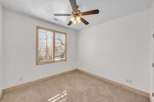 Carpeted spare room with baseboards, a textured ceiling, visible vents, and a ceiling fan