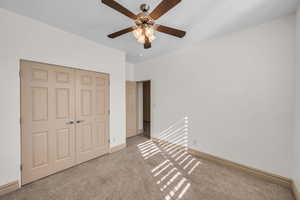 Unfurnished bedroom with ceiling fan, a closet, baseboards, and carpet flooring