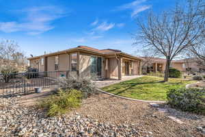 Rear view of house featuring stucco siding, a lawn, a patio area, fence, and a tiled roof