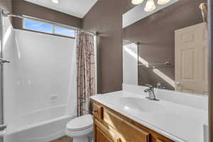 Bathroom with toilet, vanity, and shower / tub combo with curtain