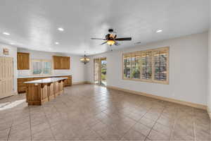 Kitchen featuring recessed lighting, a breakfast bar, a kitchen island, light countertops, and brown cabinets