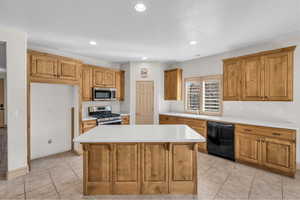 Kitchen featuring stainless steel appliances, a sink, a kitchen island, light countertops, and brown cabinets