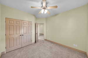 Unfurnished bedroom with a ceiling fan, carpet, a closet, and baseboards