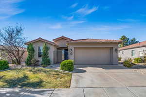 View of front of property with a garage, a tile roof, driveway, and stucco siding