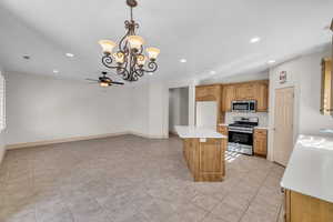 Kitchen featuring stainless steel appliances, recessed lighting, light countertops, and ceiling fan with notable chandelier