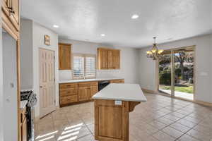 Kitchen with stainless steel gas range oven, a kitchen island, light countertops, dishwasher, and an inviting chandelier