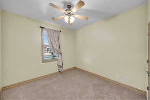 Unfurnished room with carpet flooring, ceiling fan, and baseboards