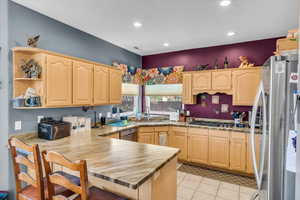 Kitchen with a sink, a peninsula, appliances with stainless steel finishes, and light brown cabinets