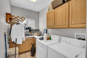 Washroom featuring light tile patterned floors, washing machine and dryer, and cabinet space