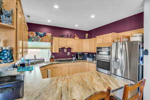 Kitchen featuring stainless steel appliances, recessed lighting, light brown cabinets, a sink, and a peninsula