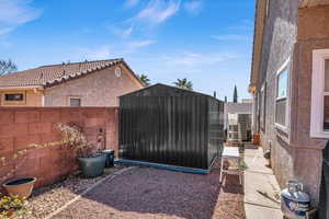 View of yard featuring a storage shed, central AC unit, an outdoor structure, and a fenced backyard