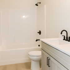 Bathroom featuring bathtub / shower combination, vanity, and light wood-style floors
