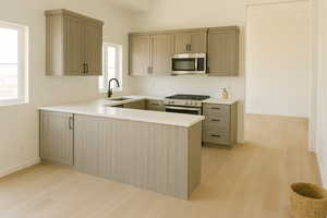 Kitchen with appliances with stainless steel finishes, light countertops, light wood-style flooring, a peninsula, and light brown cabinetry