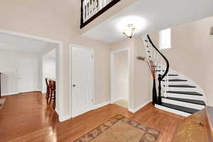 Vaulted foyer entrance with curved stairway and hardwood flooring