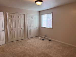 Unfurnished bedroom featuring visible vents, multiple closets, carpet flooring, and baseboards