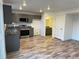 Kitchen featuring light wood-style floors, baseboards, stainless steel appliances, and a sink