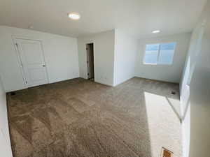 Spare room featuring carpet flooring, visible vents, and baseboards