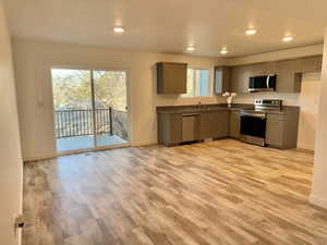 Kitchen featuring appliances with stainless steel finishes, dark countertops, gray cabinets, and light wood-style floors