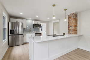 Kitchen featuring light wood-style flooring, a sink, white cabinets, appliances with stainless steel finishes, and decorative backsplash