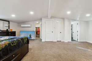 Bedroom featuring recessed lighting, lofted ceiling with beams, light carpet, a wall mounted air conditioner, and baseboards