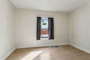 Spare room with visible vents, light wood-style flooring, and baseboards