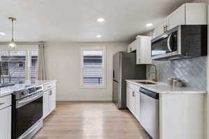 Kitchen featuring appliances with stainless steel finishes, plenty of natural light, a sink, and tasteful backsplash