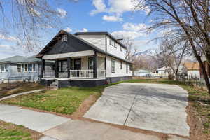 View of front of home with a front yard, covered porch, fence, and a mountain view