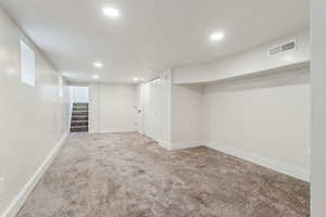 Finished basement featuring carpet, visible vents, stairway, and recessed lighting