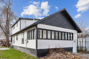 View of home's exterior with a sunroom and a lawn