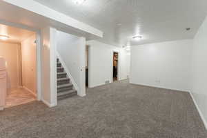 Finished second Living area featuring stairs, visible vents, carpet floors, and a textured ceiling