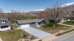 Ranch-style house with an attached garage, driveway, a front yard, a mountain view, and a shingled roof