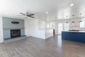 Living room with wood-like finished floors, a wealth of natural light, a fireplace, and ceiling fan
