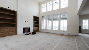 Unfurnished living room with built in shelves, heating unit, and a high ceiling