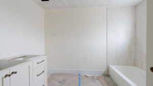 Bathroom with baseboards, a textured ceiling, and tile patterned floors