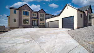Traditional-style house featuring a garage, concrete driveway, brick siding, and stucco siding