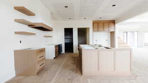 Kitchen with light brown cabinets, open shelves, a textured ceiling, and a center island