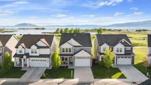 View of front of home featuring stone siding, a front yard, driveway, and a water and mountain view