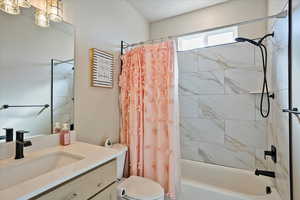 Bathroom with vanity, toilet, and shower / tub combo with curtain