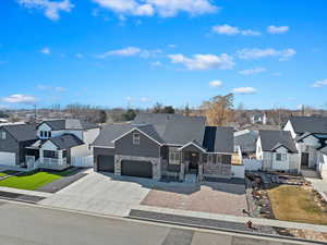 View of front of home featuring a shingled roof, concrete driveway, a garage, a residential view, and stone siding