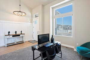 Home office with visible vents, a wainscoted wall, wood finished floors, an inviting chandelier, and a decorative wall