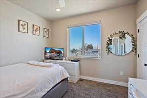 Bedroom with a textured ceiling, carpet flooring, and baseboards